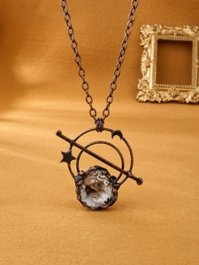 Detailweergave van vintage bronzen ketting met maanelementen en ruwe kristallen hanger