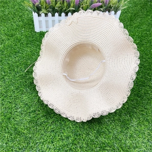 Détail d'un chapeau de paille beige avec bords festonnés et mentonnière élastique blanche
