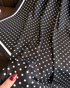 Detail eines Seidenschals mit schwarz-weißen Punkten und glatter Stofftextur im Fokus