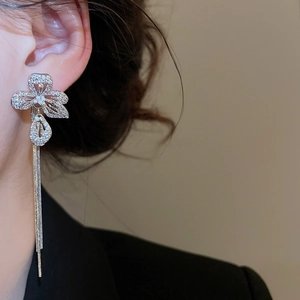 Macro detail of silver flower drop earrings with sparkling zircon tassels on a model