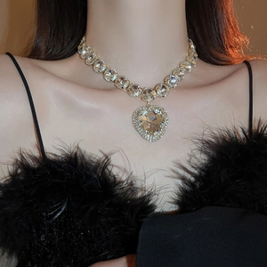 Close-up of luxury gold-tone heart crystal necklace worn by model for evening events