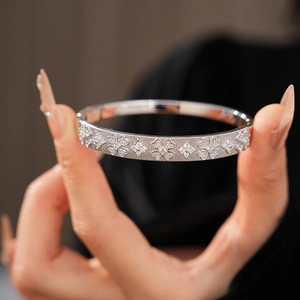 Detail of brushed silver bangle with zircon clover and starburst floral patterns