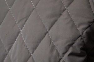 Macro detail of diamond-quilted padding on a dark grey ripstop nylon jacket