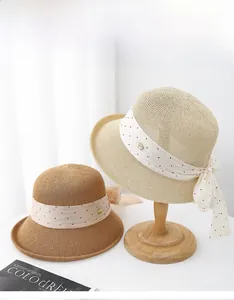 Détail d'un chapeau de paille avec ruban à pois et petit médaillon métallique élégant