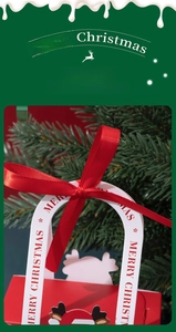 Close-up of a festive red Christmas gift box with white handles and a red satin bow