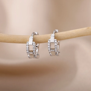 Macro shot of silver C-shaped hoop earrings featuring a geometric chain design with zircon