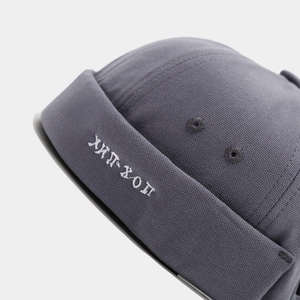 Close-up of charcoal grey docker hat showing white HIP-HOP embroidery and canvas texture