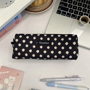 Detailed view of a black canvas polka dot pencil case on a desk with stationery items