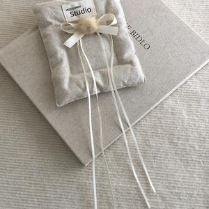 Detail of balletcore hair clip with beige fur pompom and white ribbon bow on linen