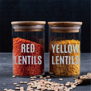 Close-up of glass jars with wood lids and silver glitter alphabet stickers for labeling