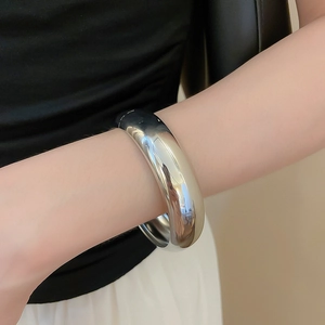 Gros plan d'un bracelet manchette large en métal argenté avec une finition polie