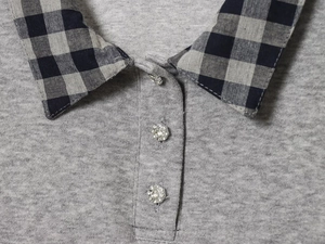 Close-up of polo knit top featuring a checkered collar and rhinestone floral buttons