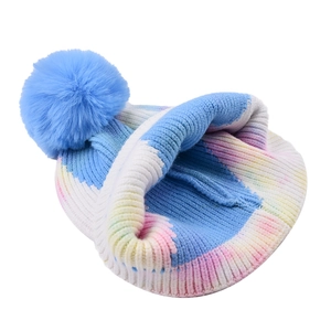 Multi-color tie-dye knit beanie with a blue faux fur pom pom for winter warmth