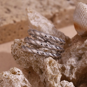 Macro shot of twisted rope design silver steel ring on a textured rock surface