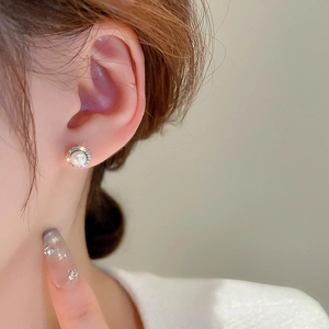 Close-up of minimalist round pearl stud earring with cubic zirconia halo on model