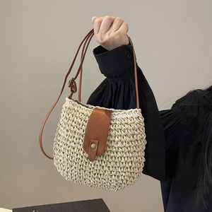 Beige woven straw shoulder bag with brown leather strap and metal buckle closure