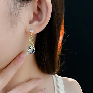 Dettaglio di orecchini vintage con smalto blu, cristalli e perle indossati da modella