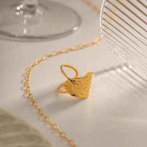 Detail of gold-plated geometric hammered ring with irregular texture on a stylish table