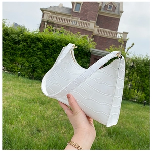 Close-up of white crocodile pattern PU leather underarm bag with gold metal zipper