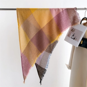 Detail of colorful plaid cashmere-like scarf with fringe edges hanging on a hanger