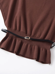 Detail of knit top hem with ruffle edge and black belt with gold oval buckle