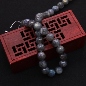 Deep grey iridescent labradorite round beads on an ornamental carved wooden box