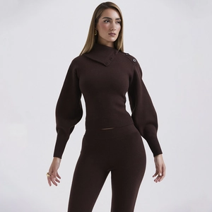 Detail of dark brown knit set featuring asymmetrical neckline with button accents