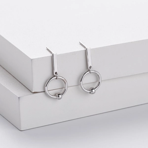 Detail of geometric silver hoop earrings on minimalist white step prop with clean lighting