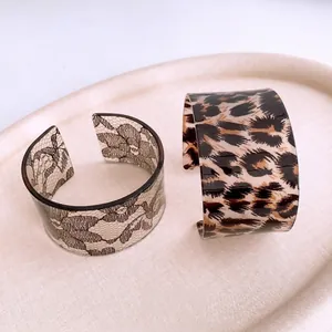 Acrylic cuff bracelets with leopard print and floral lace patterns in a minimalist tray