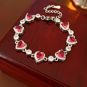 Detailansicht Silberarmband mit roten Herzsteinen und Zirkonia auf roter Schmuckschatulle