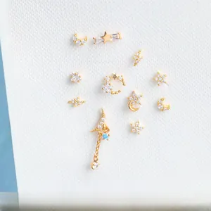 Detail of gold-plated star and moon earrings set with zircon stones on white background
