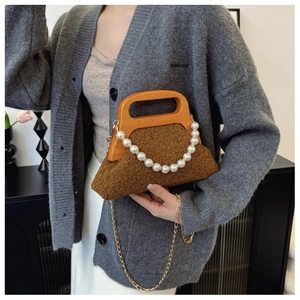 Detail of brown plush handbag featuring a wooden handle, pearl strap and golden chain