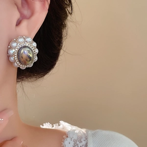 Vintage palace style stud earrings with gray faux pearl and rhinestones worn by a model