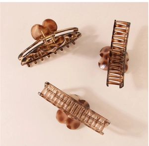 Three leopard print heart hair claws in brown plastic on a neutral beige background