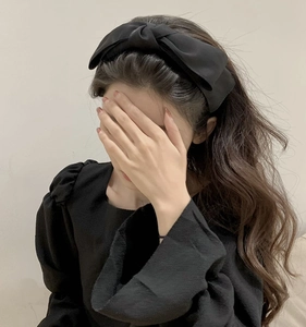 Side view of elegant black double-layered satin bow headband worn by a female model