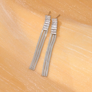 Silver fringe tassel earrings with rhinestones on a sparkling golden background