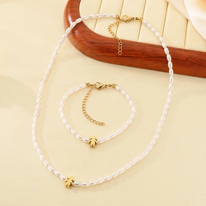 Elegant white pearl necklace and bracelet set with golden girl pendant on wood tray