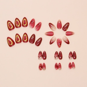 Detailed view of almond-shaped burgundy gradient press-on nails with 3D gold accents