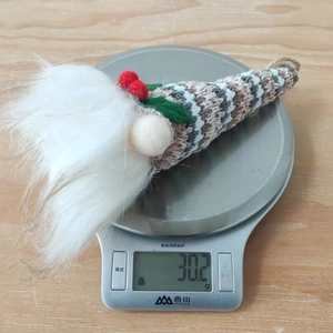 Weight measurement of a knitted Christmas gnome ornament showing 30.2g on a digital scale