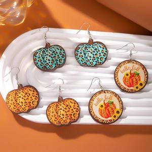 Close-up of leopard print pumpkin and hello fall wooden earrings for Thanksgiving decor
