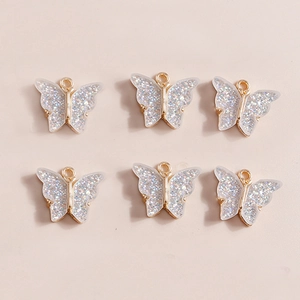Detail of six butterfly pendants with golden frames and silver glitter wings for DIY jewelry