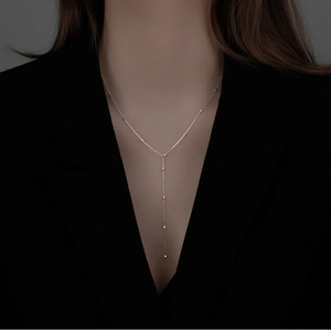 Detail view of a silver Y-shaped tassel necklace with delicate beads on a female model