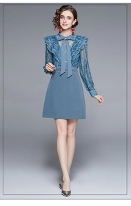 Détail d'une robe bleue en dentelle avec manches longues et décolleté à nouer