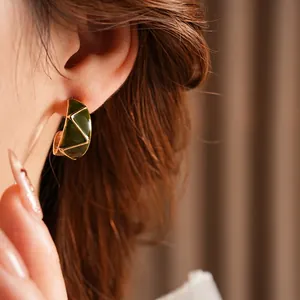 Vintage green enamel C-shaped earrings with gold trim worn by a model in soft lighting