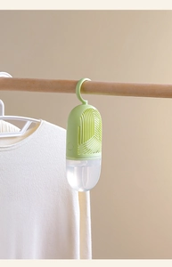 Close-up of hanging wardrobe dehumidifier with green top hook and water collection bag