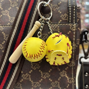 Detail of mini baseball glove and bat keychain accessory hanging on a patterned bag