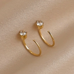 Elegant gold-plated geometric C-shape hoop earrings with clear zircon on silk background