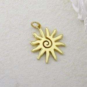 Detailed view of a gold-plated sun pendant with spiral design and cubic zirconia inlay