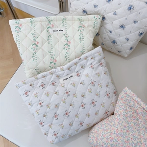 Close-up of quilted floral cosmetic bags with diamond stitching and woven brand labels