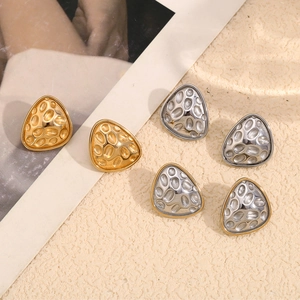Macro detail of irregular triangle stud earrings with 18K gold and silver hammered texture